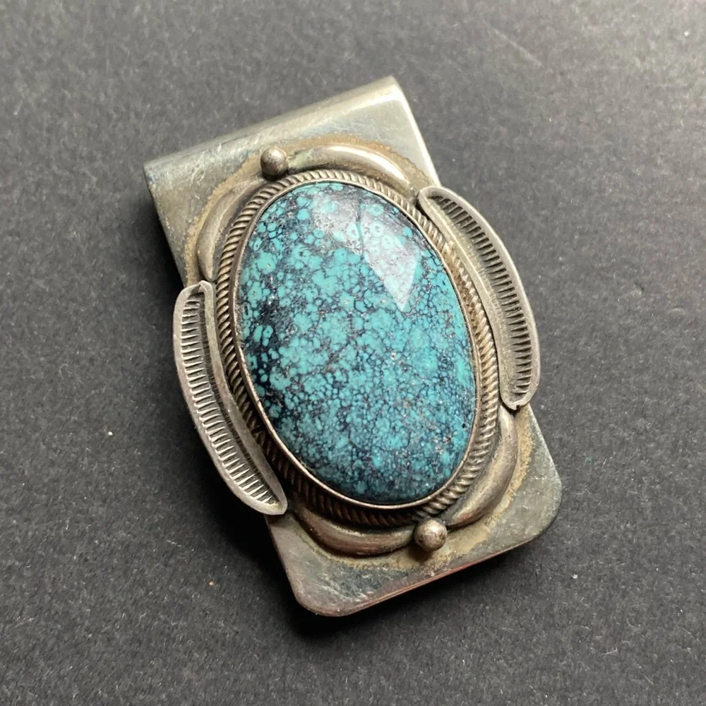 Silver toned money clip with polished blue stone. No stamps.